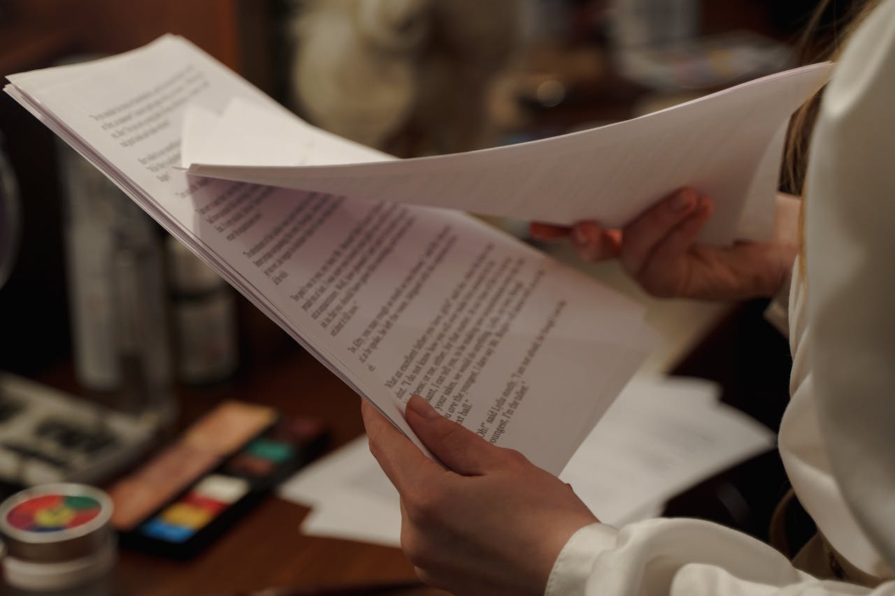 A woman holds and reads a script in a dressing room, preparing backstage for a theatrical performance.